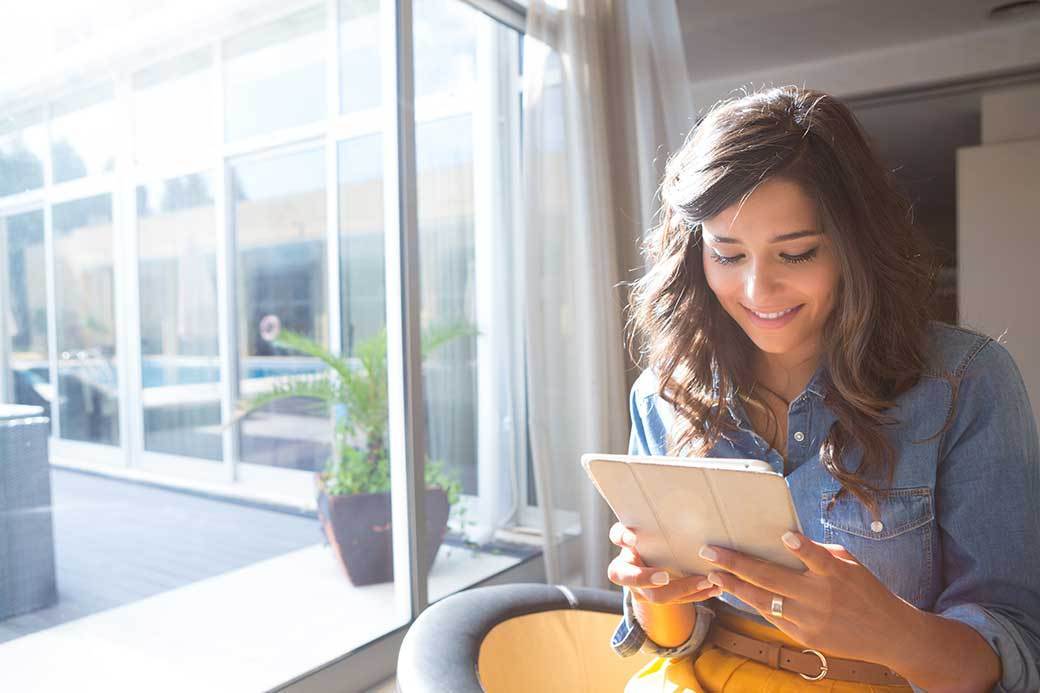 Woman sitting in window looking at a tablet
