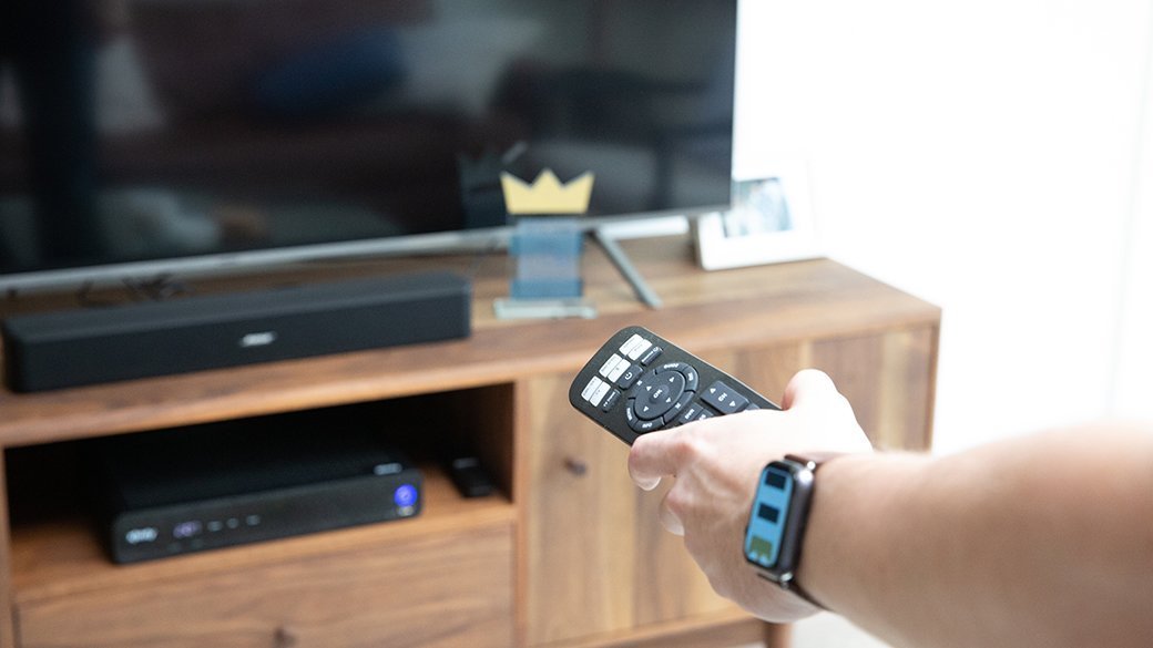 Person pointing remote at sound bar